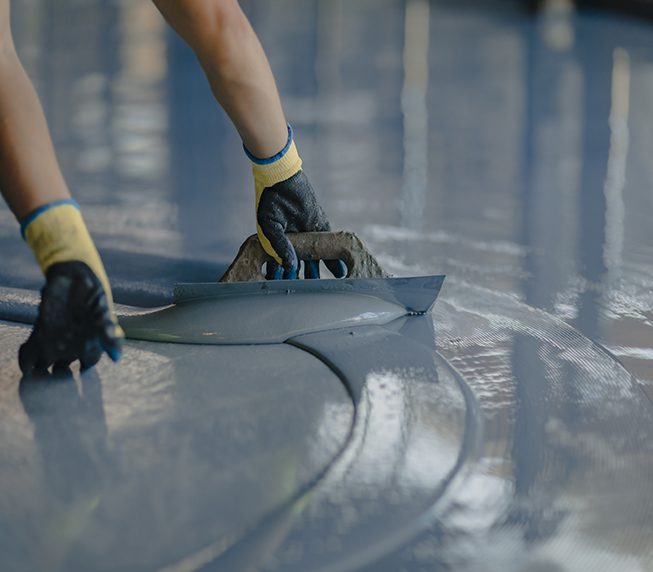 The worker applies gray epoxy resin to the new floor